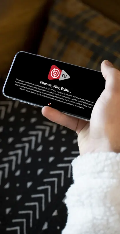 User holding smartphone with IBO Player App streaming interface on screen